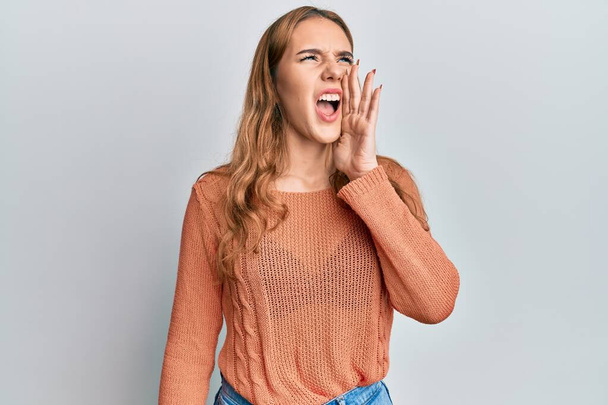 Young blonde woman wearing casual clothes shouting and screaming loud to side with hand on mouth. communication concept.  - Photo, Image