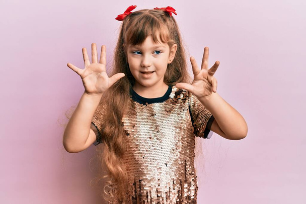 Malá kavkazská dívka dítě na sobě slavnostní flitry šaty ukazující a ukazující nahoru s prsty číslo devět a zároveň se usmívá sebevědomě a šťastně.  - Fotografie, Obrázek
