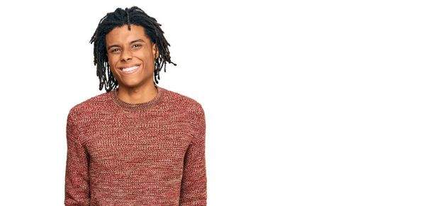 Молодий афроамериканець, одягнений у звичайний зимовий светр, виглядає позитивним і щасливим, стоїть і усміхається з упевненою усмішкою, що показує зуби.  - Фото, зображення