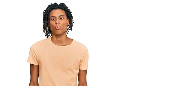 Fiatal afro-amerikai férfi alkalmi ruhát visel, halfejet vágva ajkakkal, őrült és vicces gesztussal. Vicces kifejezés..  - Fotó, kép