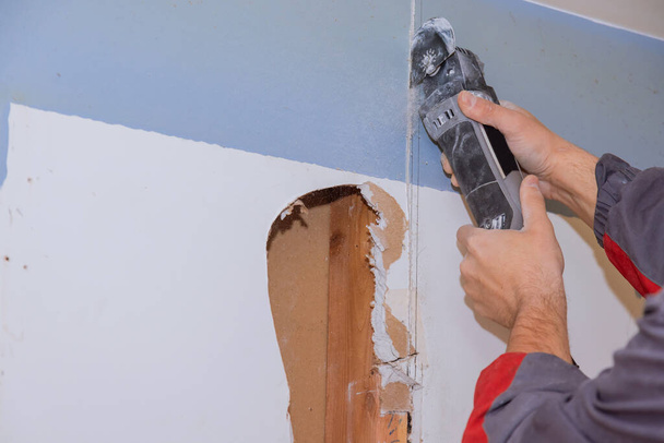 角度ハンド電動工具を使用して人間の切断石膏ボードの修理の家とドライウォールボードのための改修住宅の改善アパートの内部損傷 - 写真・画像