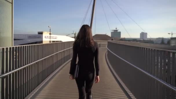 Geïsoleerde full length portret van jonge Europese zakenvrouw in zwarte jurk met bruin haar naar voren lopen. Achteraanzicht. - Video