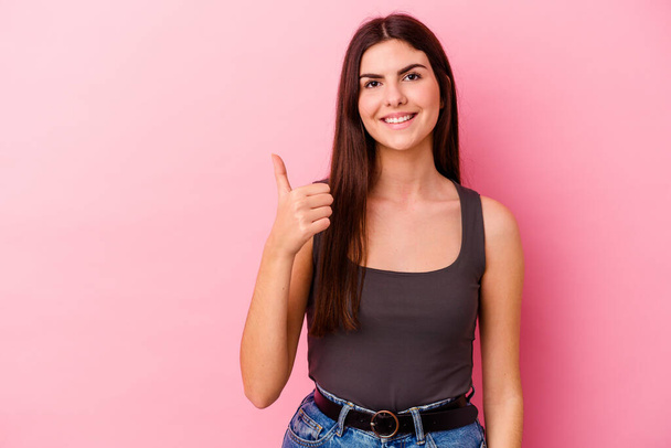 jonge Kaukasische vrouw geïsoleerd op roze achtergrond glimlachen en het verhogen van duim omhoog - Foto, afbeelding