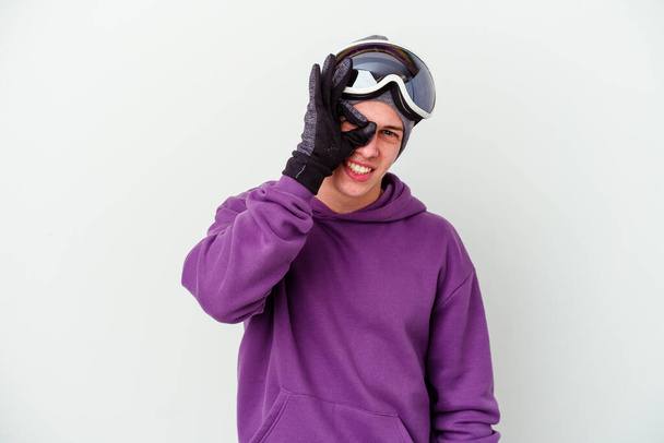 Joven sosteniendo una tabla de snowboard aislado sobre fondo blanco emocionado manteniendo el gesto bien en el ojo. - Foto, Imagen