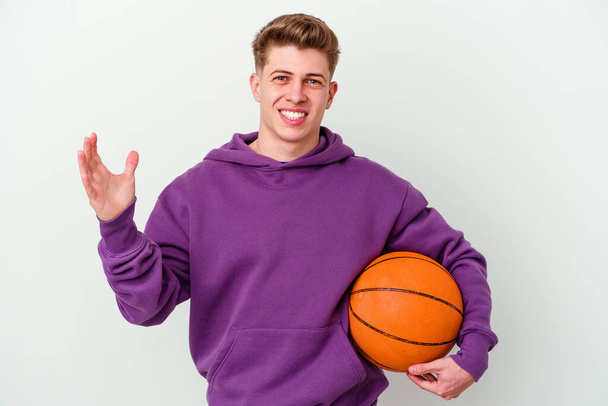 Νεαρός καυκάσιος που παίζει μπάσκετ απομονωμένος, δέχεται μια ευχάριστη έκπληξη, ενθουσιάζεται και σηκώνει τα χέρια.. - Φωτογραφία, εικόνα
