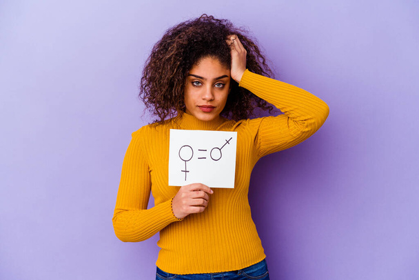 Young African American woman holding a gender equality placard isolated on purple background being shocked, she has remembered important meeting. - Photo, Image