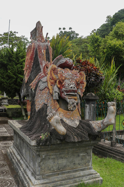 Статуя барона в Тирта Ганга Водный дворец Таман Тиртаганга, бывший дворец царей в Карангасеме, Бали, Индонезия. Традиционная балийская статуя Баронга в Бали, Индонезия - Фото, изображение