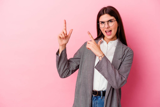 Young caucasian business woman isolated on pink background pointing with forefingers to a copy space, expressing excitement and desire. - Photo, Image