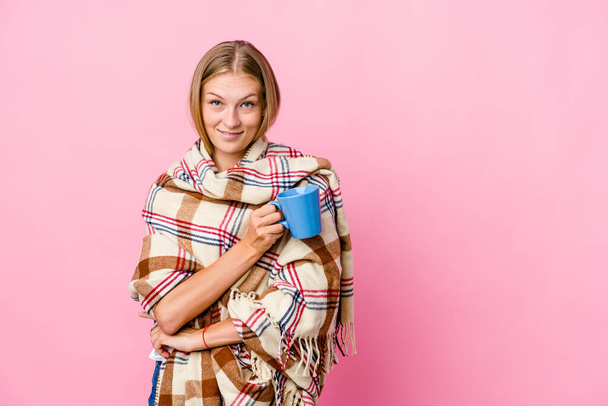 Genç Rus kadın battaniyeye sarılıp kahvesini yudumlarken kollarını kavuşturup gülümsüyor.. - Fotoğraf, Görsel