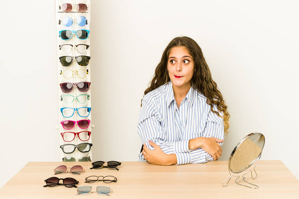 Junge kaukasische Frau versucht Brille isoliert verwirrt, fühlt sich zweifelhaft und unsicher. - Foto, Bild