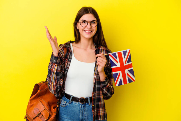Nuori nainen opiskelee Englanti eristetty vaaleanpunainen tausta vastaanottaa miellyttävä yllätys, innoissaan ja nostamalla kädet. - Valokuva, kuva