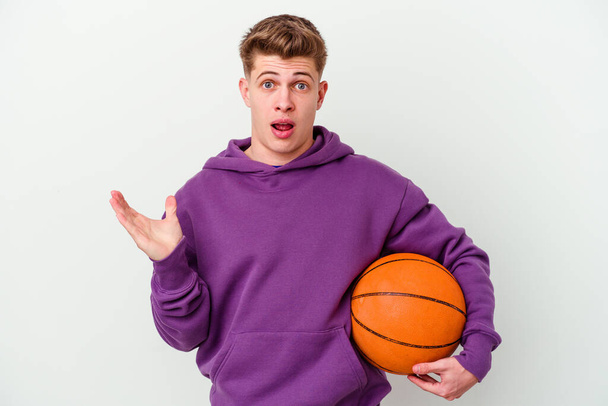 Молодий білий чоловік грає в баскетбол ізольований фон здивований і шокований
. - Фото, зображення