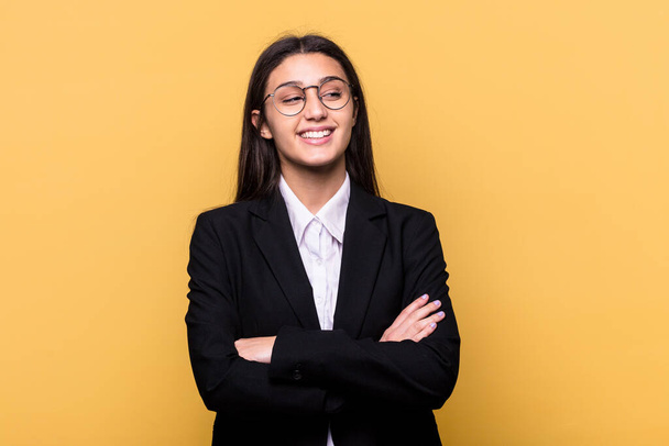 Young Indian business woman isolated on yellow background smiling confident with crossed arms. - Fotó, kép