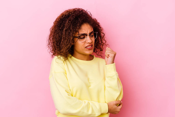 Jovem afro-americana isolada sobre fundo rosa confusa, sente-se duvidosa e insegura. - Foto, Imagem