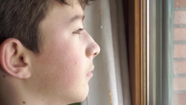 Smutny samotny nastolatek wygląda troskliwie przez okno. nastrój melancholijny - Materiał filmowy, wideo