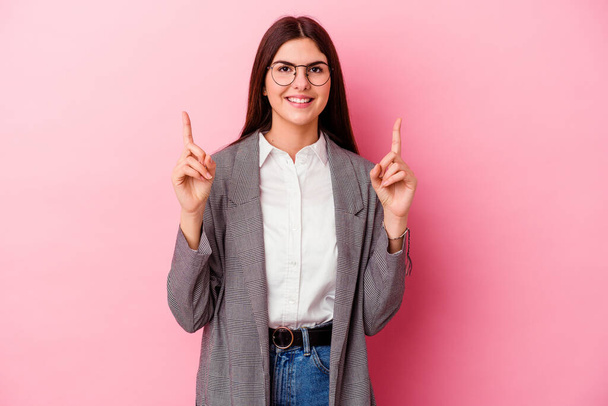 Young caucasian business woman isolated on pink background indicates with both fore fingers up showing a blank space. - Photo, Image