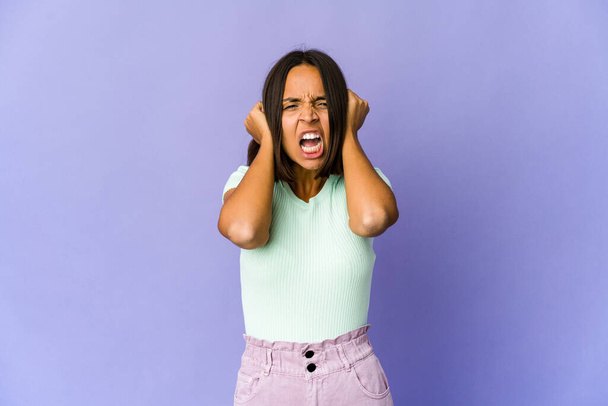 Joven mujer de raza mixta cubriendo los oídos con las manos tratando de no escuchar un sonido demasiado fuerte. - Foto, imagen