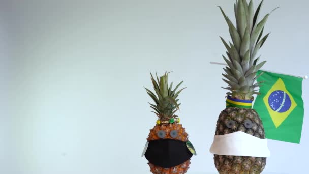 De ananas draagt een gezichtsmasker. het begrip "crisiscoronavirus" (COVID-19). Kopieerruimte. - Video