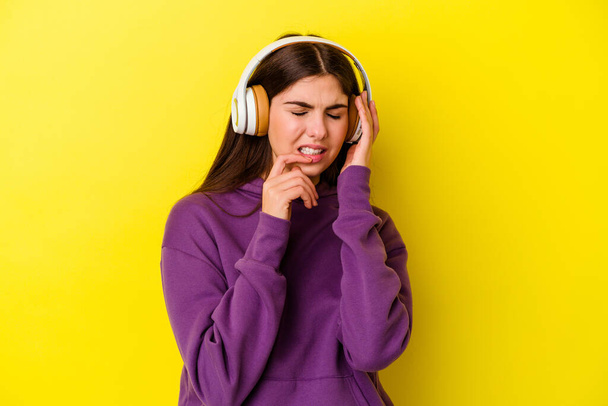 Young caucasian woman listening to music with headphones isolated on pink background whining and crying disconsolately. - Fotó, kép