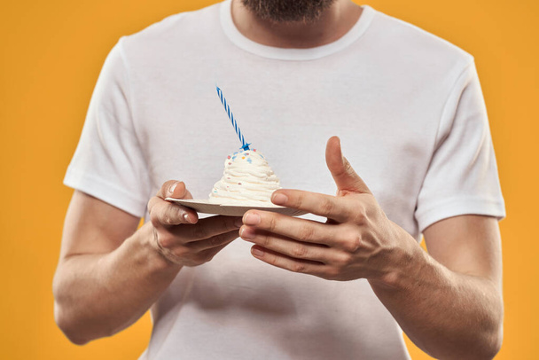 A man with a birthday cake in his hands on a yellow background birthday dessert - Fotografie, Obrázek