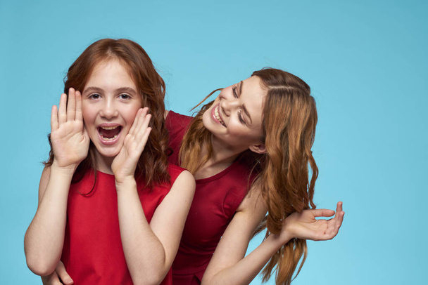 Mamá e hija en vestidos rojos entretenimiento estilo de vida divertido estudio fondo azul - Foto, Imagen