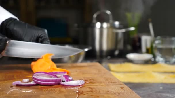 Chef en guantes negros cocinando rebanadas de verduras en la tabla de cortar. Cazuela hirviendo con vapor en el fondo. Preparación de alimentos veganos. Comida saludable, cocina casera, dieta, comida dietética, comida vegetariana. 4 k - Imágenes, Vídeo