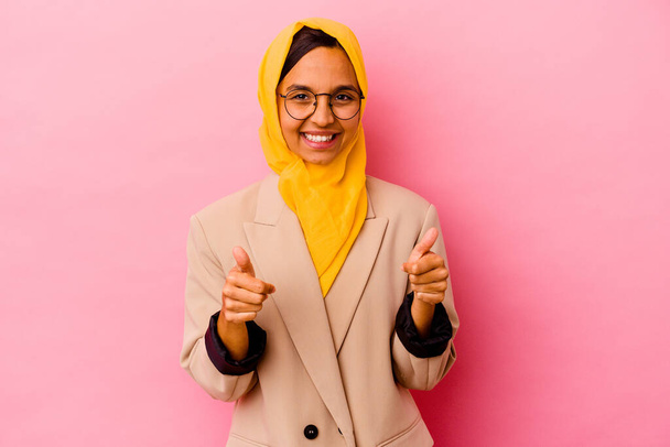 ピンクの背景に親指を立てて孤立した若いビジネスのイスラム教徒の女性、何かについての歓声、サポートと尊敬の概念. - 写真・画像