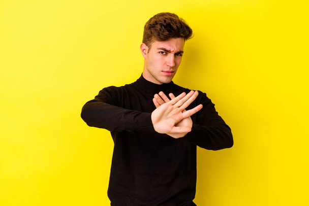 Νεαρός καυκάσιος άνδρας απομονωμένος σε κίτρινο φόντο κάνει μια χειρονομία άρνησης - Φωτογραφία, εικόνα