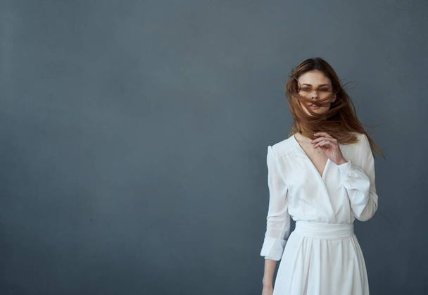 Vrouw in witte jurk mooie kapsel glamour en luxe bijgesneden uitzicht grijze achtergrond - Foto, afbeelding