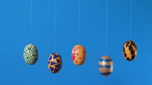 Barevná velikonoční vajíčka se točí kolem své osy na modrém pozadí s místem pro text. Velikonoční prodej, slevy nebo propagační akce v propagačním videu. - Záběry, video