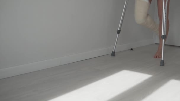 A woman on crutches with a broken leg moves  - Footage, Video