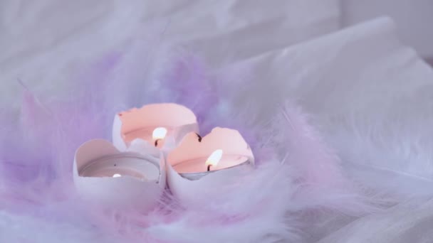 Zusammensetzung aus weißer Eierschale mit brennender Kerze im Inneren. Kerzenschein. Leuchtende Osterdekorationen mit Vogelfedern. Pastellfarben. Flammenrauch - Filmmaterial, Video