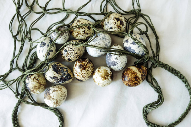 μικρά αυγά ορτυκιού με στίγματα σε οικολογική πράσινη σακούλα. επαναχρησιμοποιήσιμα πράγματα για χρήση. αναλογική μεταφορά τροφής. κορυφαία προβολή, επιλεκτική εστίαση - Φωτογραφία, εικόνα