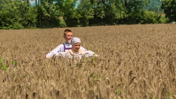 Двое детей, двигающихся по пшеничному полю с вытянутыми руками. Slow Motion - Кадры, видео