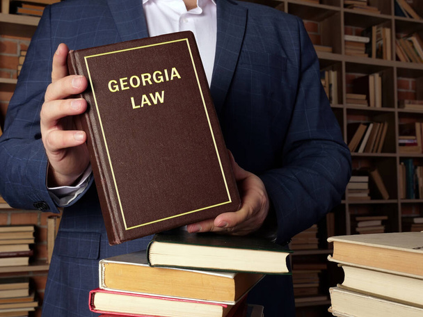 Attorney holds GEORGIA LAW book. Georgia residents are subject to Georgia state and U.S. federal law - Foto, imagen