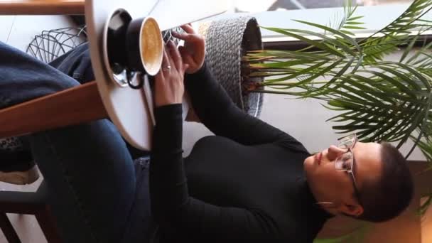 Una mujer se sienta en un café y trabaja en un portátil. - Metraje, vídeo