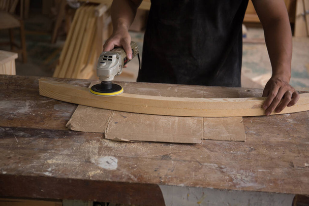 Schuurmachine, De timmerman maakt gebruik van een polijstmachine om het hout glad te strijken. - Foto, afbeelding