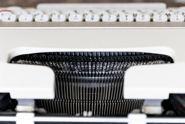 Foto van een typemachine van bovenaf, met de nadruk op de metalen delen die de letters op het papier drukken. De typemachine is wit. - Foto, afbeelding