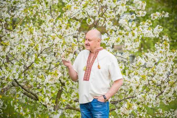 Starší muž v vyšívané košili v květinové zahradě - Fotografie, Obrázek