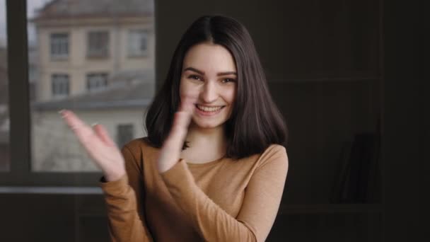 Portré kaukázusi fiatal lány tinédzser kaukázusi modell mosolyog néz kamera pózol egyedül otthon beltéri tapsoló kezét, tapsoló kezét, díjak győzelem elismerését, kifejezi öröm hála - Felvétel, videó
