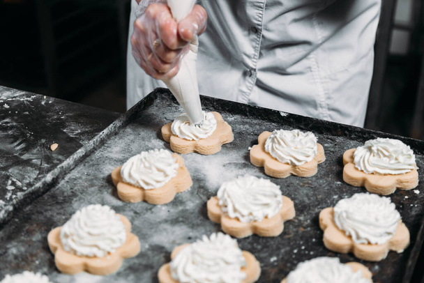 Chefs hands with pastry bag squeezing out cream dough for baking  - Photo, Image