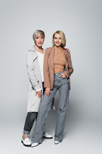 trendy, middle aged woman with young, stylish daughter posing on grey - Zdjęcie, obraz