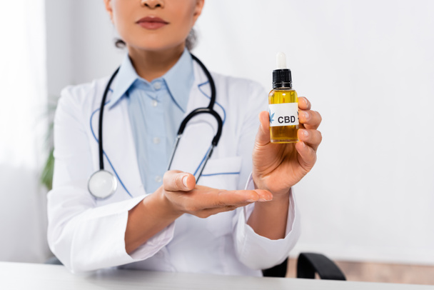 cropped view of african american doctor pointing with hand at bottle with cbd  - Photo, Image