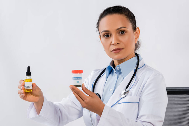 african american doctor holding cbd and medical cannabis bottles  - Photo, Image