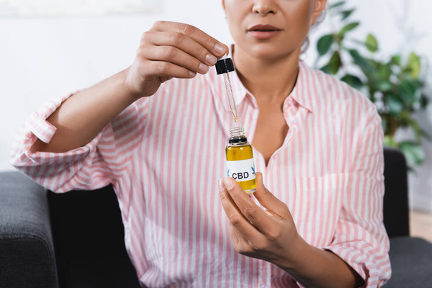 cropped view of african american woman holding bottle with cbd lettering and pipette  - Photo, Image