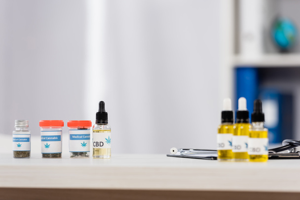 botellas con cannabis medicinal y letras cbd cerca del portapapeles en el escritorio - Foto, imagen