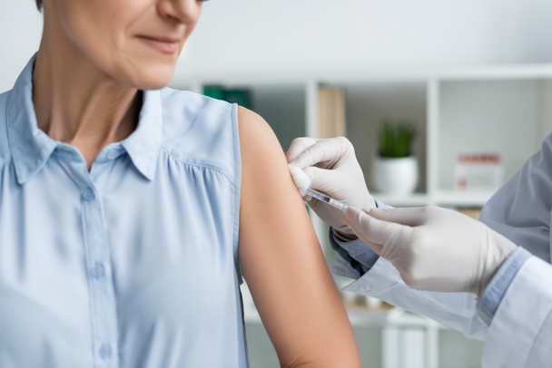 Oříznutý pohled na lékaře provádějícího očkování dospělé ženy  - Fotografie, Obrázek