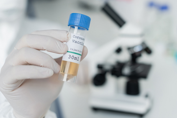 Cropped view of scientist in latex glove holding coronavirus vaccine in laboratory  - Photo, Image