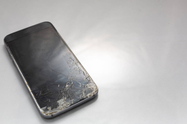Close-up van gebroken glazen scherm op een smartphone, geïsoleerd tegen een witte achtergrond - Foto, afbeelding