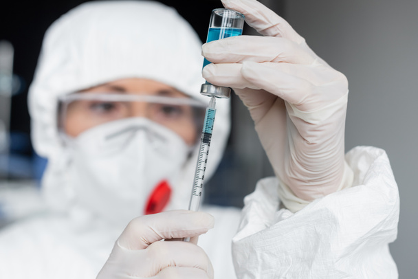 Scientist on blurred background picking up vaccine in syringe   - Photo, Image